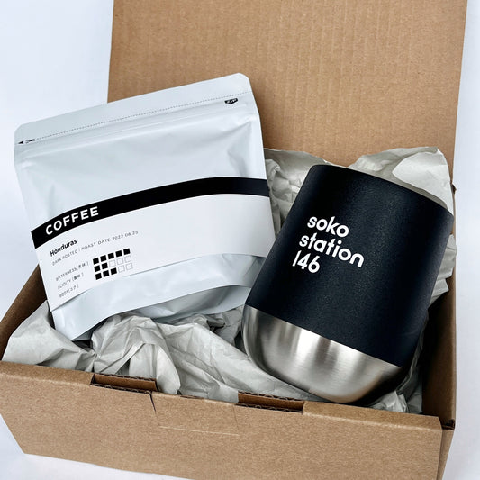 コーヒー豆(2種のうち1種)と、黒とシルバーのサーモタンブラーが入ったシンプルでミニマルなデザインのコーヒーギフトセット