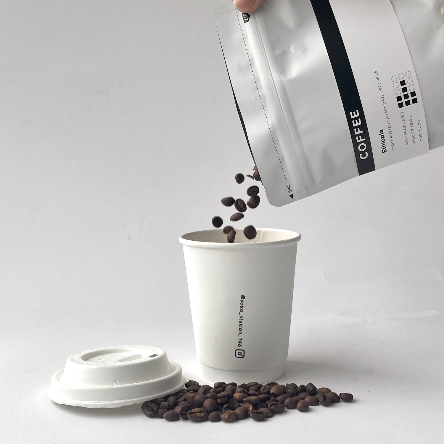 コーヒー豆（2種のうち1種）と、白とシルバーのサーモタンブラーが入ったシンプルでミニマルなデザインのコーヒーギフトセット